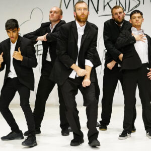 group of 5 male dancers in suits on a white stage