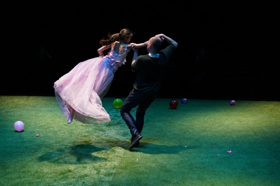 A man dances with a young teenage girl in a pink ball gown